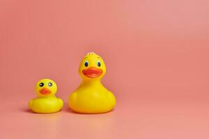 dois brinquedos de patos de borracha amarelos, copie o espaço. brinquedos de banho engraçados fofos, conceito mínimo de kidult. fundo rosa. foto