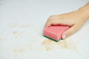 esponja na mão da mulher remove sujeira, migalhas de pão e sobras. limpeza da mesa da cozinha. tarefas domésticas foto