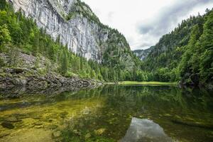 calma montanha lago com reflexão e pedra arestas sobre pinho árvores dentro uma nublado dia. unesco mundo herança site, nacional parque dentro austríaco Alpes. pacífico natureza paisagem, Primavera verão cenário foto