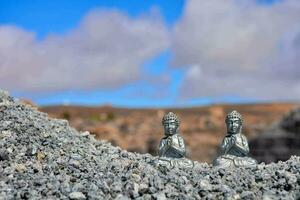 dois pequeno Buda estátuas estão sentado em topo do uma pilha do pedras foto