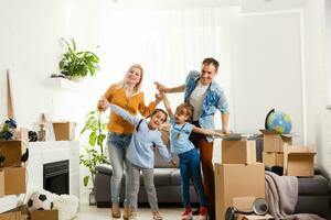 feliz família com cartão caixas dentro Novo casa às comovente dia. foto