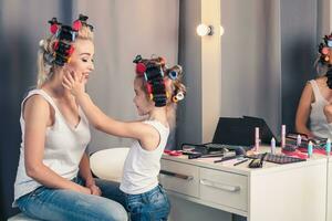 mãe e dela criança menina estão fazendo seu Maquiagem e tendo Diversão foto