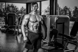 bonito homem com grande músculos, posando às a Câmera dentro a Academia foto