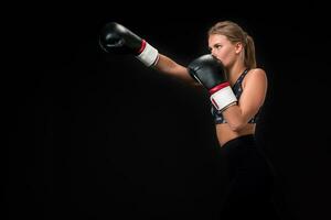 lindo fêmea atleta dentro boxe luvas, dentro a estúdio em uma Preto fundo. foto