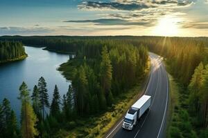 ai gerado aéreo Visão do uma caminhão dirigindo ao longo a estrada dentro a floresta às pôr do sol, aéreo Visão do uma semi-caminhão com uma carga reboque em uma estrada curva às a lago costa com uma verde pinho floresta foto