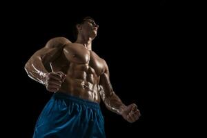 muscular e em forma jovem fisiculturista ginástica masculino modelo posando sobre Preto fundo. foto