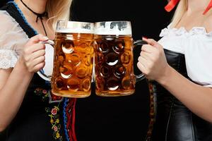 jovem e lindo bávaro meninas com dois Cerveja canecas em Preto fundo foto