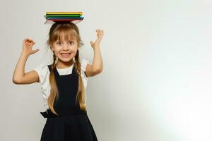 pequeno engraçado menina dentro camisa com livros. isolado em branco fundo. bebê menina dentro escola. a criança menina com livros didáticos. menina estudando. foto