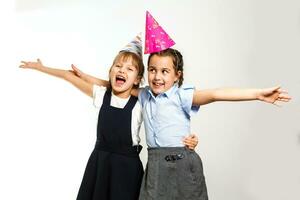 dois aniversário meninas dentro camisa azul escola uniforme vestidos chapéu isolado em branco fundo crianças estúdio retrato. infância crianças Educação estilo de vida conceito. zombar acima cópia de espaço foto