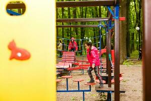 adorável pequeno menina desfrutando dela Tempo dentro escalada aventura parque foto