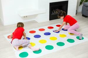 dois pequeno meninas tendo Diversão jogando jogos em chão às lar. irmãos amizade foto