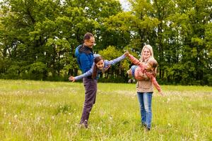 jovem familiy estão caminhando através uma verde campo foto