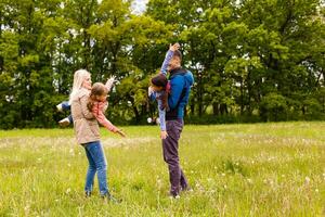 jovem familiy estão caminhando através uma verde campo foto