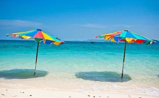 cadeira de praia sob a égide de colorido na praia de phuket, tailândia foto