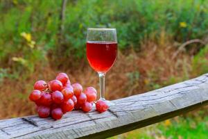 copo de vinho tinto e cacho de uvas na mesa de madeira foto