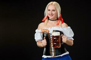 jovem sexy mulher vestindo uma dirndl com Cerveja caneca em Preto fundo. foto