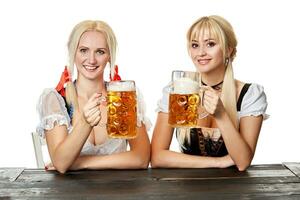 dois lindo mulheres segurando uma vidro do Cerveja enquanto sentado às uma de madeira mesa em uma branco fundo dentro a estúdio foto