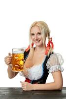 jovem bávaro mulher dentro dirndl sentado às mesa com Cerveja em branco fundo foto
