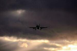 uma avião vôo através a nuvens com Sol raios chegando através foto