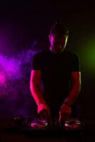 atraente jovem dj jogando em gira-discos com cor luz efeitos foto