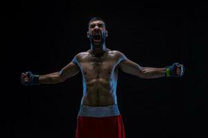 oriental boxer a comemorar dele vitória com elevado braços dentro Preto luvas em Preto fundo foto