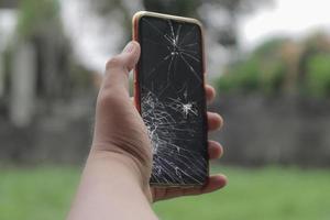 mão segurando o vidro do lcd do celular quebrado rachado e quebrado foto