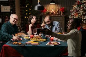 pessoas levando fotos às festivo jantar, fazer recordações do Natal véspera celebração às lar. diverso amigos e família tendo Diversão com bebidas e comida, levando As fotos com Smartphone.