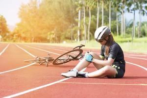 garota tem lesão por acidente esportivo no joelho por causa do conceito de bicicleta, esporte e acidente foto