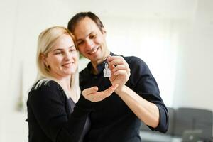 feliz sorridente jovem casal mostrando uma par do chaves do seus Novo casa foto