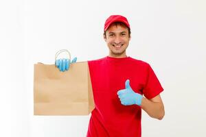 sorridente jovem Entrega homem segurando e carregando uma Caixa de papelão isolado em branco fundo foto