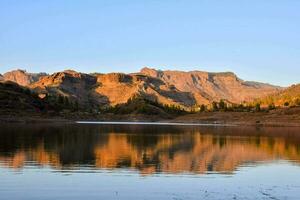 a montanhas estão refletido dentro a água às pôr do sol foto