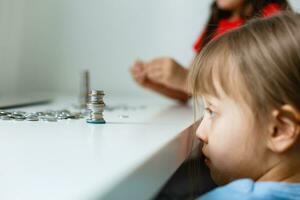 fofa pequeno menina jogando com moedas fazer pilhas do dinheiro, criança salvando dinheiro para a futuro conceito foto