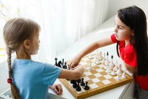 dois pequeno irmã jogando xadrez às casa foto