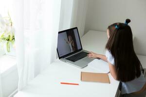 pequeno menina estudando com computador portátil conectados Aprendendo foto