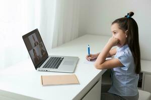 alegremente fofa menina crianças animado usando computador Aprendendo trabalho escolar. criança apreciar e-learning dentro feriado às lar. foto