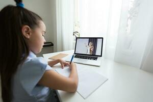 alegremente fofa menina crianças animado usando computador Aprendendo trabalho escolar. criança apreciar e-learning dentro feriado às lar. foto