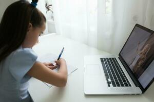 pequeno menina estudando com computador portátil conectados Aprendendo foto