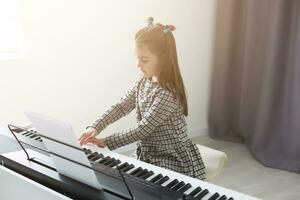 lindo menina com salão ondulação jogando uma piano dentro apartamento foto