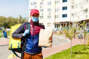 Entrega homem mandar Comida saco às porta botão para sem contato ou contato livre a partir de Entrega cavaleiro dentro frente casa para social distanciar para infecção risco. foto