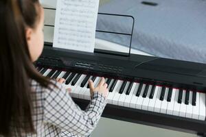 lindo menina com salão ondulação jogando uma piano dentro apartamento foto