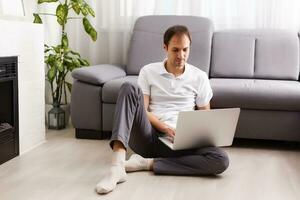 feliz sorridente jovem homem assistindo e trabalhando em computador computador portátil às casa foto