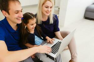 feliz pais com filha usando computador portátil às casa foto