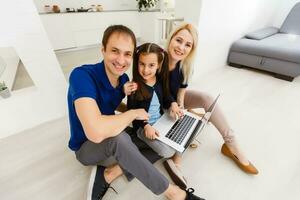 feliz pais com filha usando computador portátil às casa foto