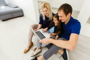 família topo Visão sentado em chão usando computador portátil computador dentro dela quarto às casa foto