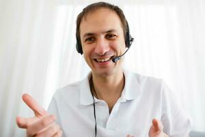 feliz homem de negocios dentro a escritório em a telefone, fone de ouvido, Skype. olhando Câmera foto