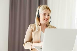 alegre mulher vestem fone de ouvido rir usando computador portátil vídeo corrente conferência ligar Ensinar on-line, feliz étnico menina aluna jogador tutor ter Diversão Assistir webinar rede cam Educação entretenimento conceito foto