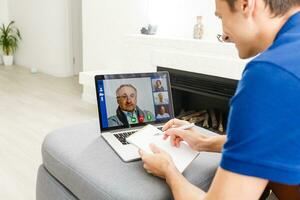 feliz sorridente jovem homem assistindo e trabalhando em computador computador portátil às casa foto