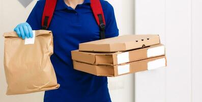 Entrega homem empregado dentro vermelho boné camiseta uniforme mascarar luvas dar Comida ordem pizza caixas isolado em amarelo fundo estúdio. serviço quarentena pandemia coronavírus vírus gripe 2019-ncov conceito foto