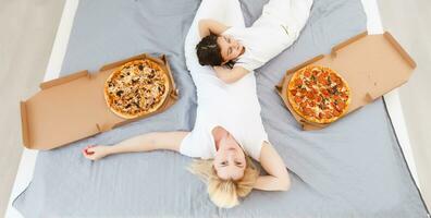 mãe e filha comendo pizza. relaxante às casa foto