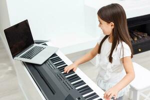 bonita jovem músico jogando clássico digital piano às casa durante conectados classe às lar, social distância durante quarentena, isolamento voluntário, conectados Educação conceito foto